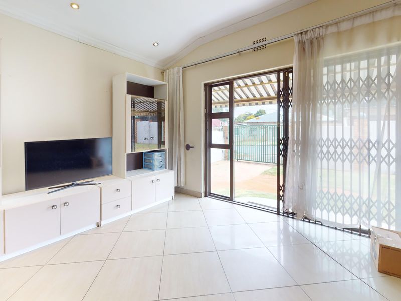 Spacious living room featuring tiled flooring, built-in cabinetry, and a sliding glass door providing direct access to the outdoor area.