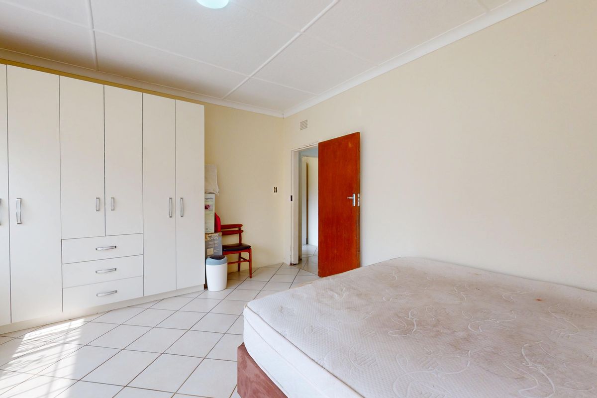 A bedroom featuring tiled flooring and a large built-in wardrobe with ample storage space.