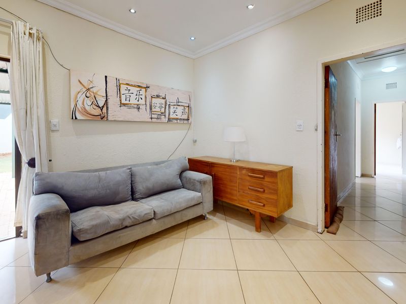 A living room featuring tiled flooring, recessed downlighting, and a sliding glass door providing access to the outdoor area.