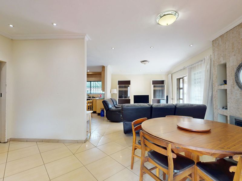 Spacious open-plan living and dining area featuring tiled floors, recessed lighting, and a stone-clad feature wall with a built-in fireplace.