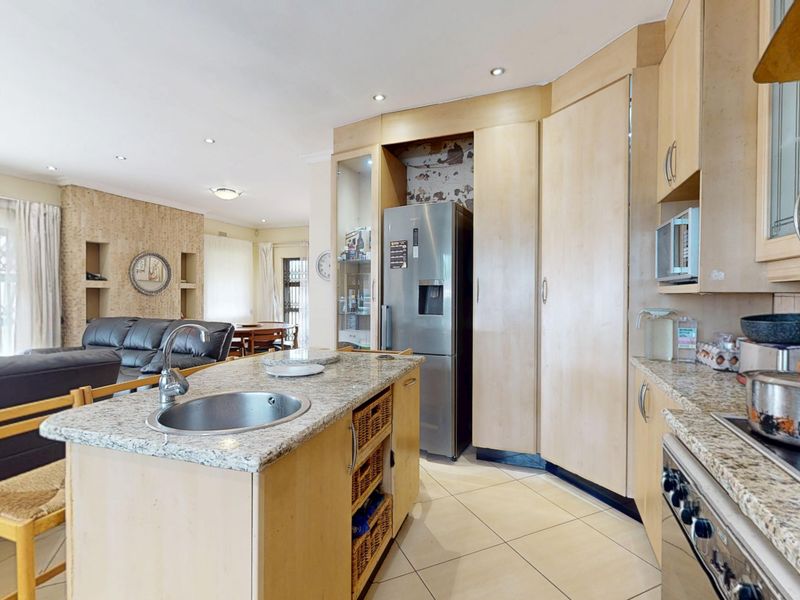 Open-plan kitchen and living area featuring granite countertops, a central island with sink, and built-in cabinetry with integrated appliance space.