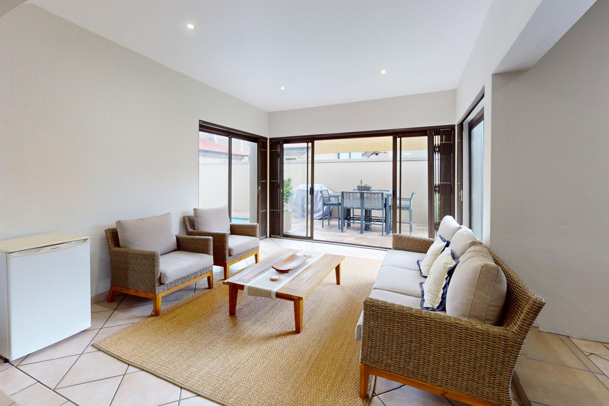 Bright and airy living room featuring tiled flooring and large sliding glass doors that provide seamless access to the outdoor patio area.
