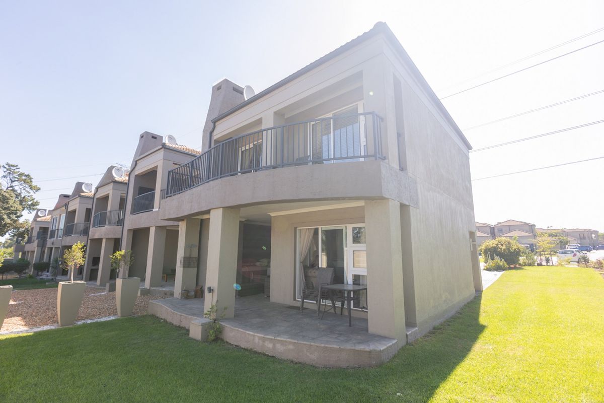 Rear view of a townhouse featuring a covered ground-floor patio, an upper-level balcony with metal railings, and sliding door access.