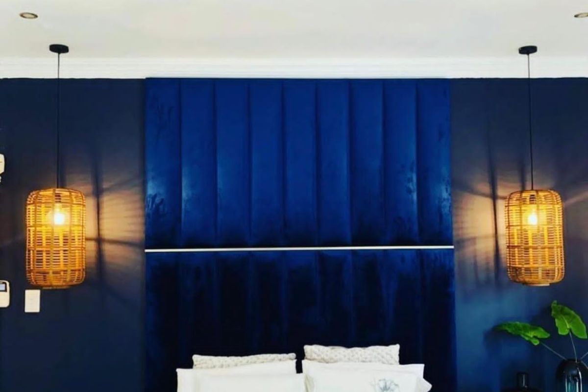 A well-appointed bedroom featuring a striking deep blue upholstered feature wall and integrated recessed lighting.