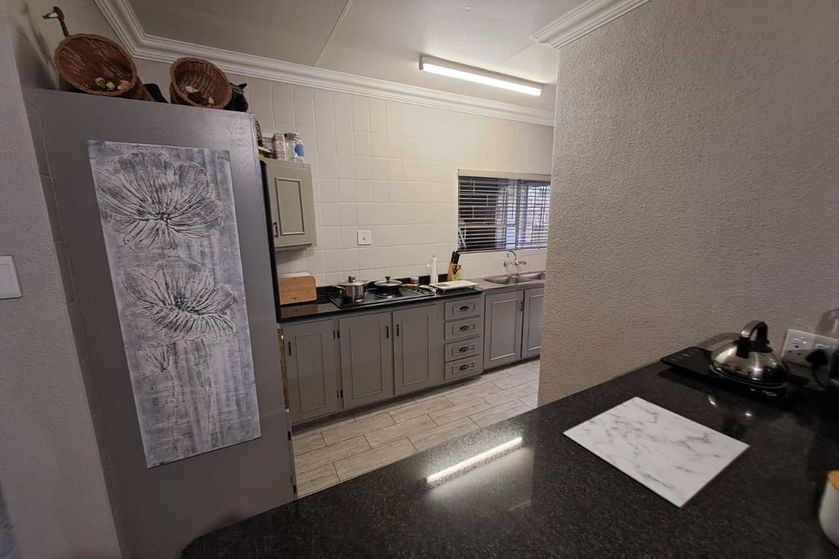 Functional kitchen featuring grey cabinetry, dark granite countertops, tiled backsplash, and tiled flooring with a practical layout.