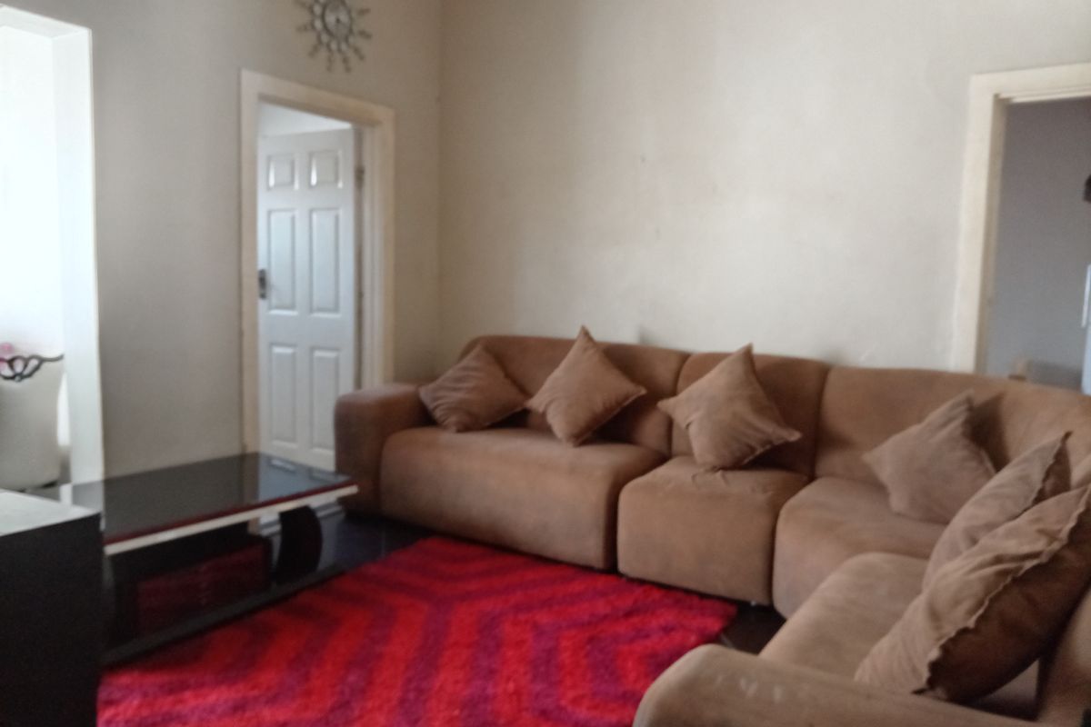 A living room space featuring neutral walls and access to adjacent rooms through standard interior doorways.