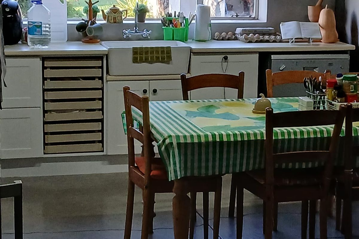 A functional kitchen area featuring a farmhouse-style sink, white cabinetry, and tiled flooring, providing a practical space for food preparation and dining.