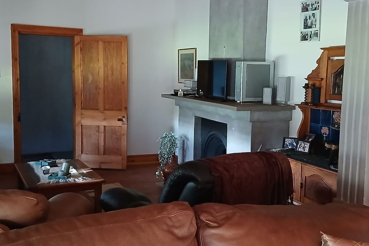 A living room featuring a prominent concrete fireplace surround, wooden door frames, and timber skirting boards.