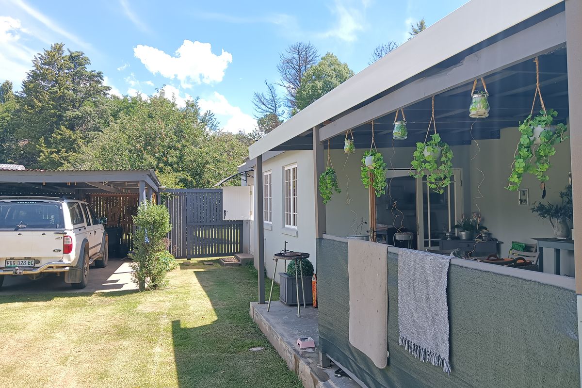 A view of the rear exterior featuring a covered patio area, a lawn, and a detached carport structure.