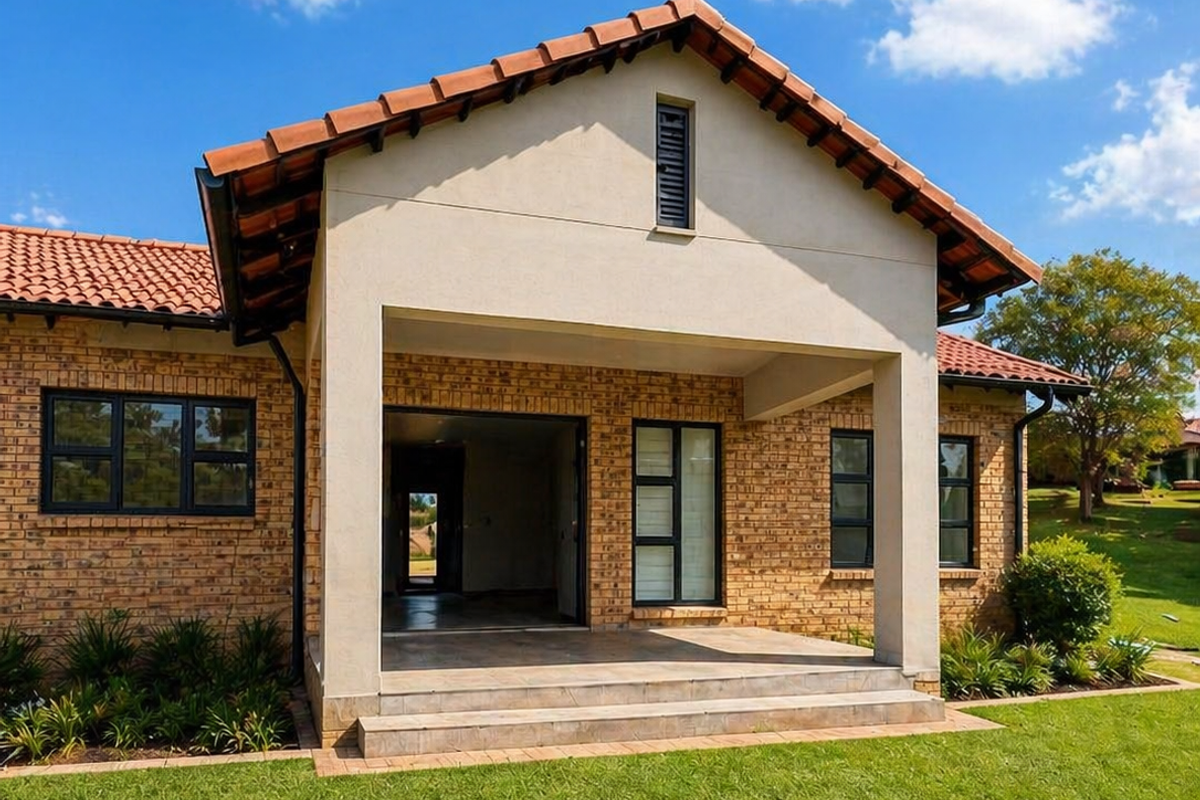 A well-maintained retirement village home featuring a classic face brick exterior, terracotta roof tiles, and a spacious covered patio overlooking a manicured lawn.