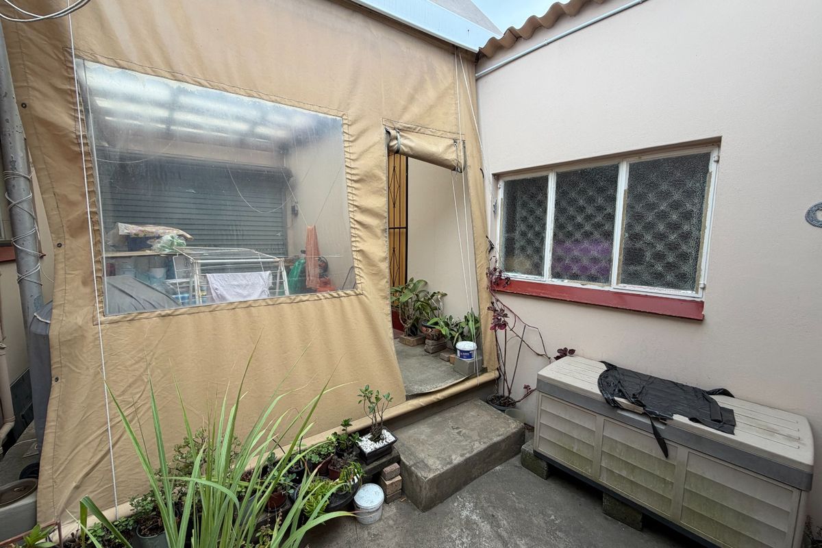 A rear courtyard area featuring a concrete patio and a canvas-enclosed outdoor space, providing a functional but dated exterior utility area.