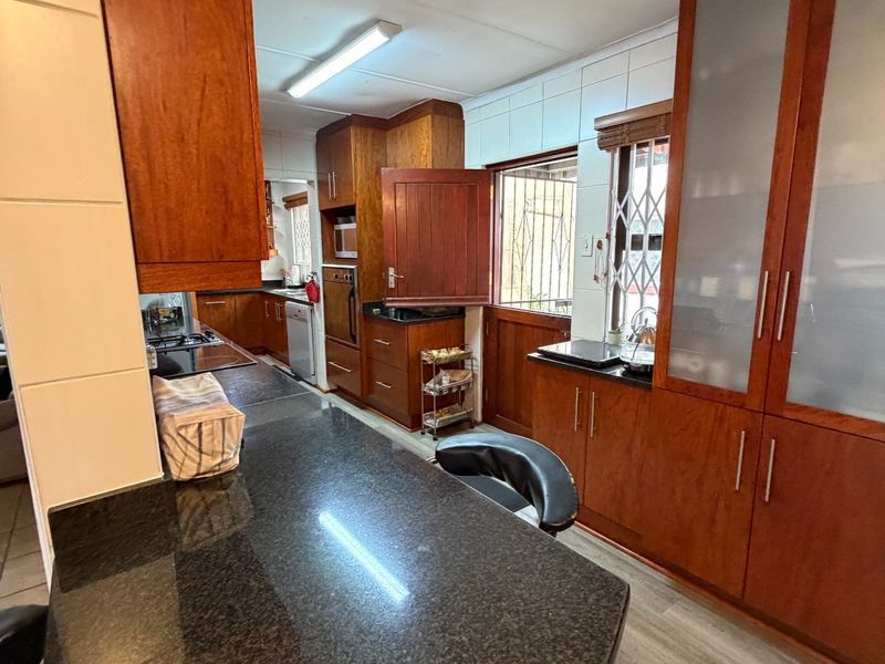 A functional kitchen featuring dark granite countertops, extensive wooden cabinetry, and a built-in oven, providing ample storage and workspace.