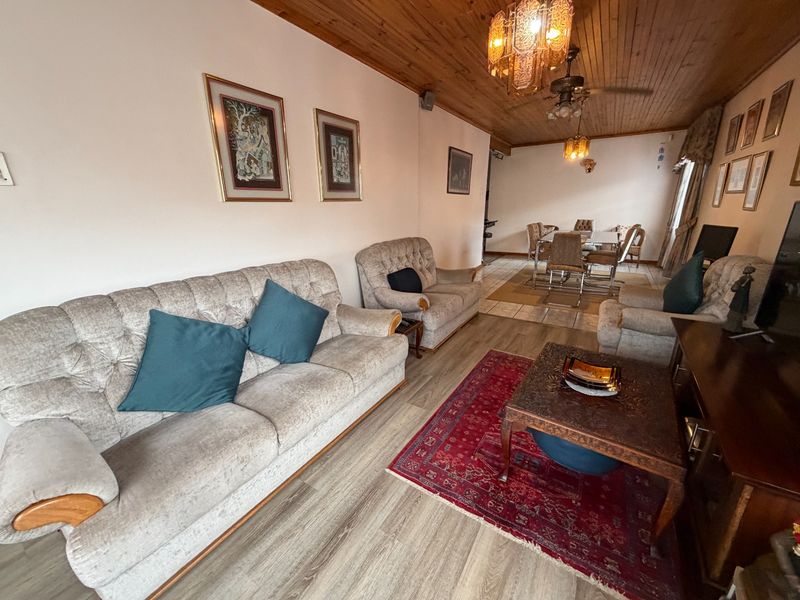 Spacious open-plan living and dining area featuring timber tongue and groove ceilings, laminate flooring, and integrated ceiling fan lighting.