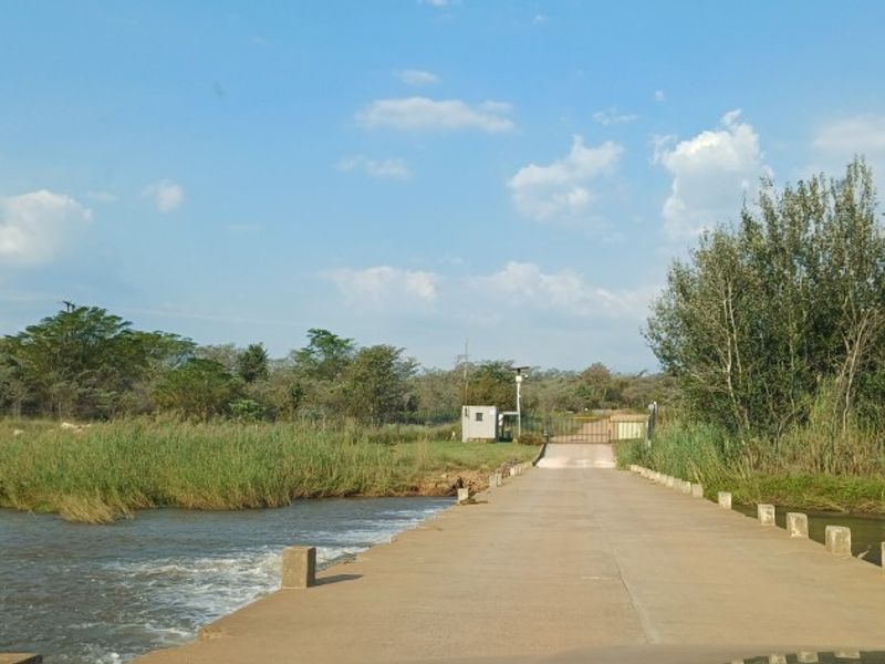 A concrete bridge providing access to the property, featuring a security gate and guard house set against a natural landscape.