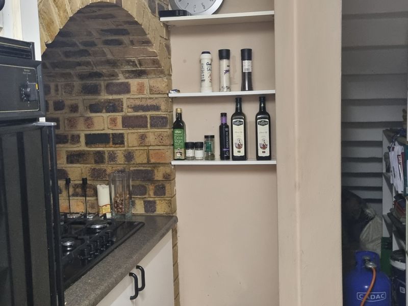 Kitchen area featuring a built-in oven, gas hob, stone countertop, and a distinctive brick arch detail with integrated shelving.