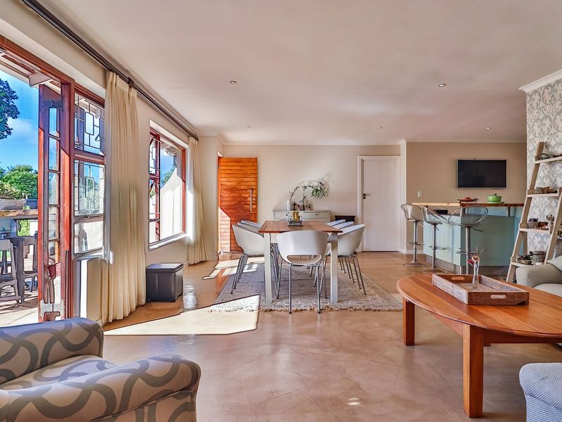 Spacious open-plan living and dining area featuring polished concrete floors, large sliding doors opening to a patio, and a built-in breakfast bar.