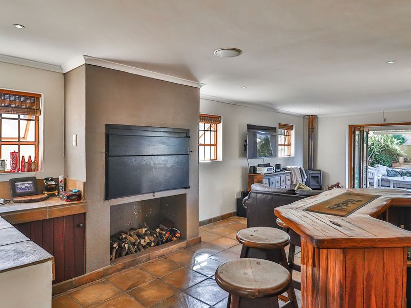 Spacious open-plan living area featuring a built-in fireplace, tiled flooring, and direct access to an outdoor patio through folding doors.