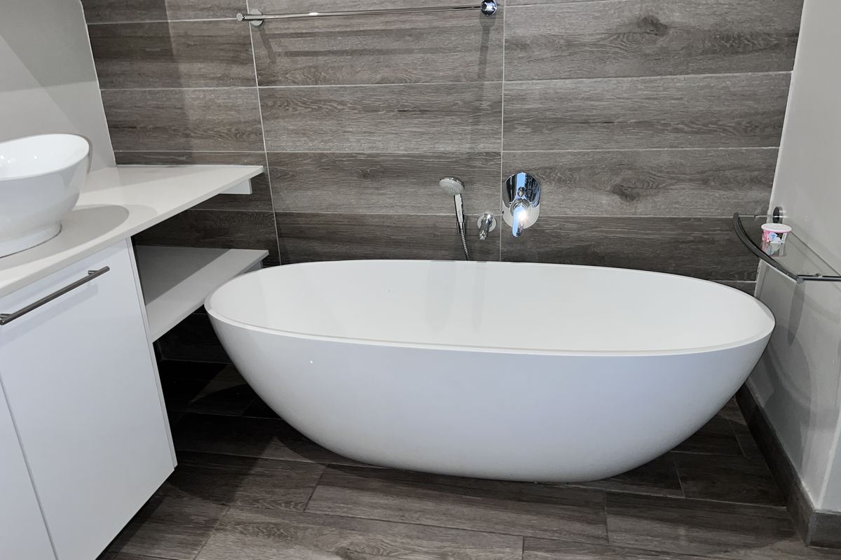 Modern bathroom featuring a sleek freestanding bathtub, vessel sink vanity, and contemporary wood-look tile finishes throughout.