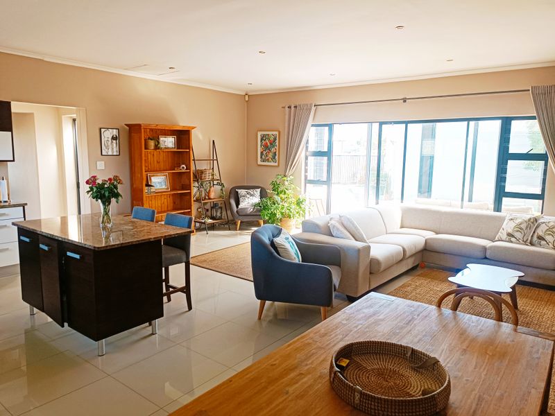 Spacious open-plan living area featuring a kitchen island with granite countertops, tiled flooring, and large sliding glass doors leading to the exterior.