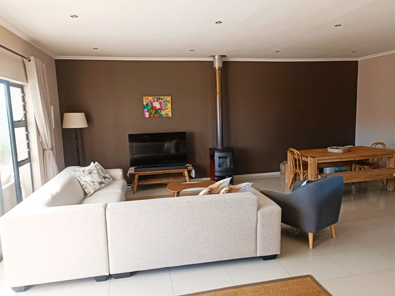 Spacious open-plan living and dining area featuring tiled floors, recessed lighting, and a modern freestanding fireplace, creating a comfortable and functional living space.