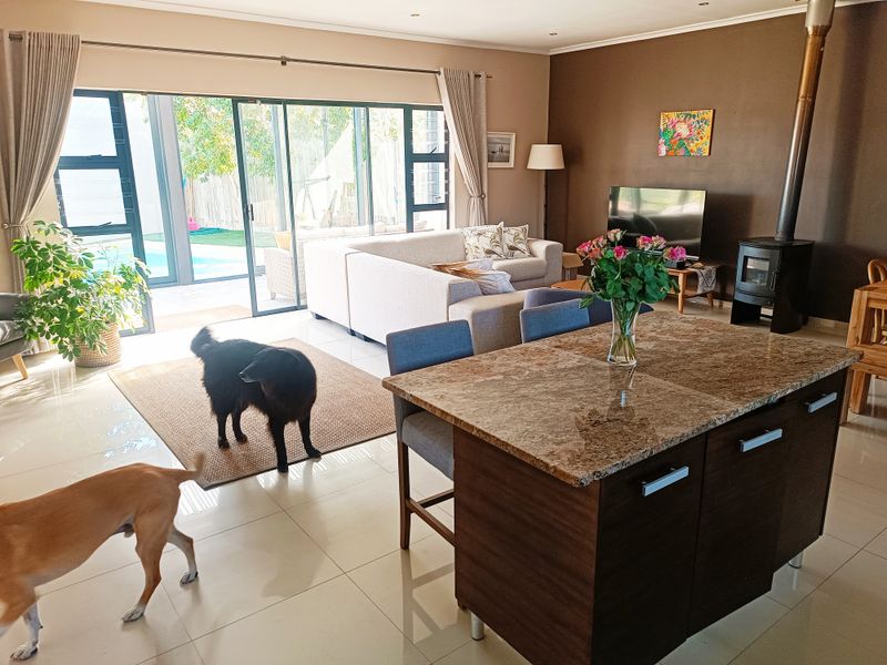 Spacious open-plan living area featuring a modern kitchen island, a freestanding fireplace, and large sliding glass doors that open to the outdoor pool area.