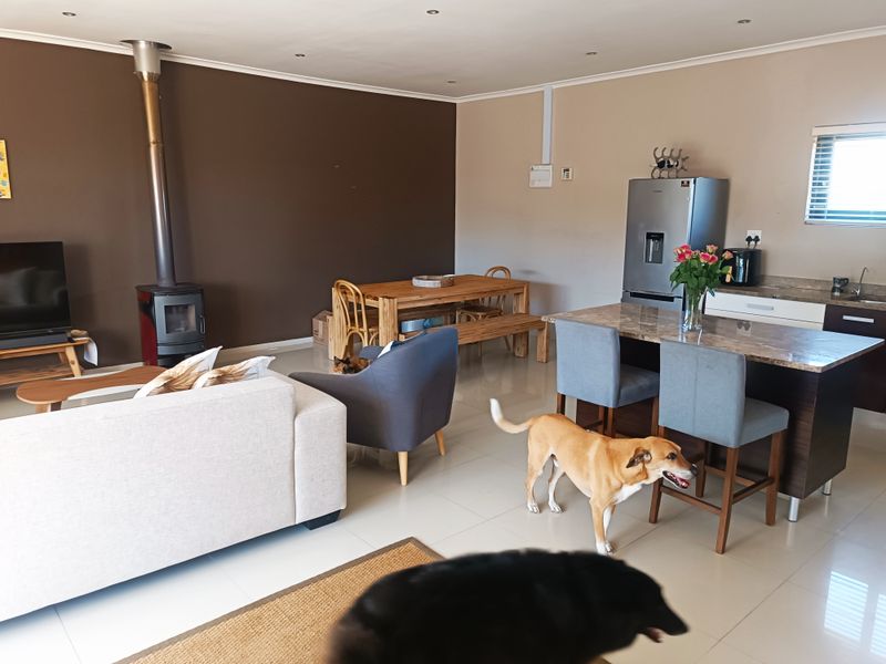 Spacious open-plan living area featuring a modern kitchen island with granite countertops, tiled flooring, and a cozy freestanding fireplace.