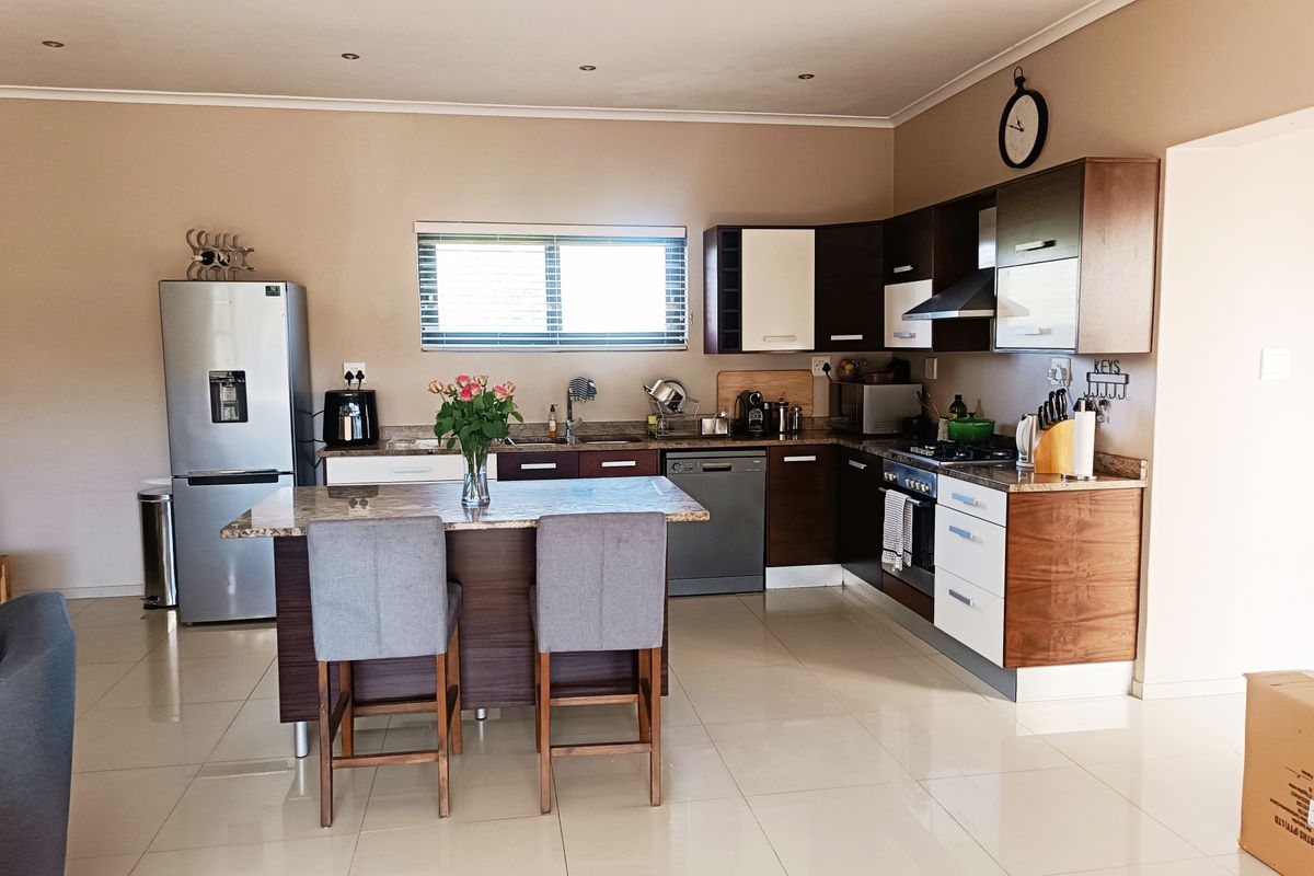 Modern kitchen featuring dark and white cabinetry, granite countertops, a central island, and integrated appliances, finished with sleek tiled flooring and recessed lighting.