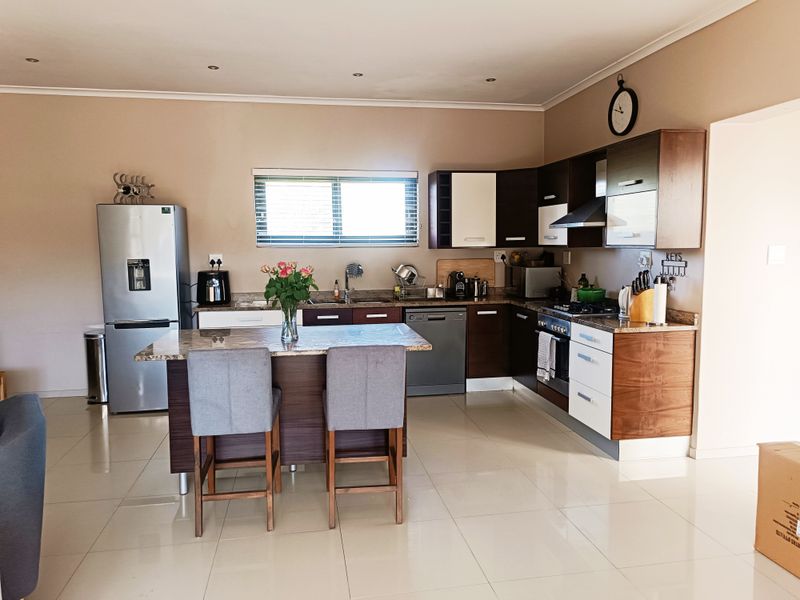 Modern kitchen featuring dark and white cabinetry, granite countertops, a central island, and integrated appliances, finished with sleek tiled flooring and recessed lighting.