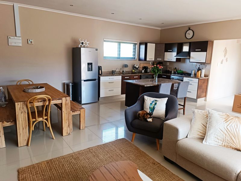 Spacious open-plan living and dining area featuring a modern kitchen with granite countertops, built-in appliances, and sleek porcelain floor tiles throughout.