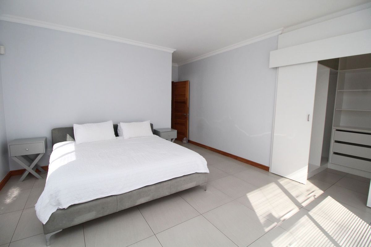 Spacious bedroom featuring neutral tiled flooring, built-in wardrobe with shelving, and classic crown molding.