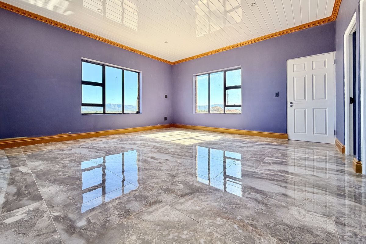 Spacious bedroom featuring polished marble-look floor tiles, decorative crown molding, and a tongue and groove ceiling with ample natural light.