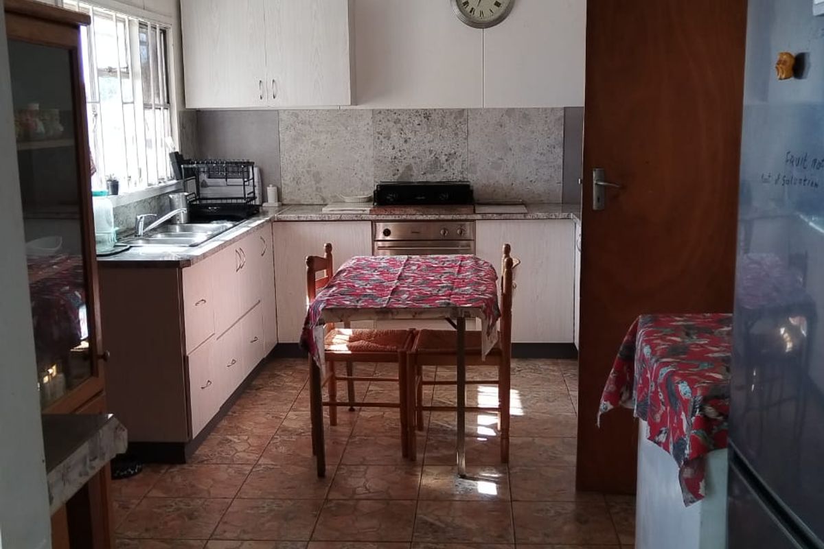 A functional kitchen featuring built-in cabinetry, a stainless steel oven and hob, tiled flooring, and a double sink with a window view.