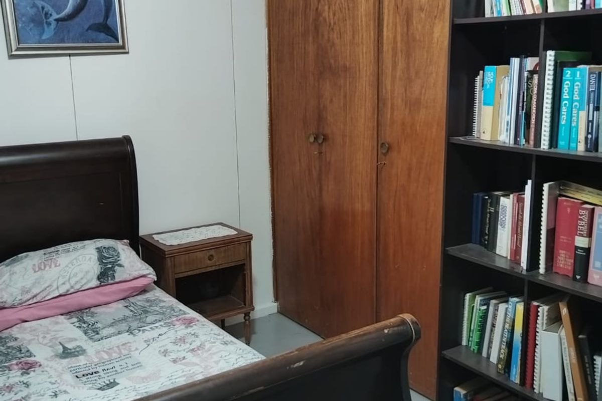 A bedroom featuring built-in wooden cupboards and panelled walls, offering functional storage space.