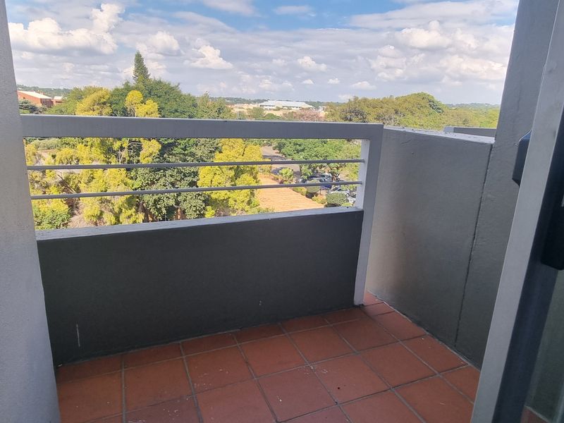 A private balcony featuring tiled flooring and a metal balustrade, offering an elevated view of the surrounding neighborhood.