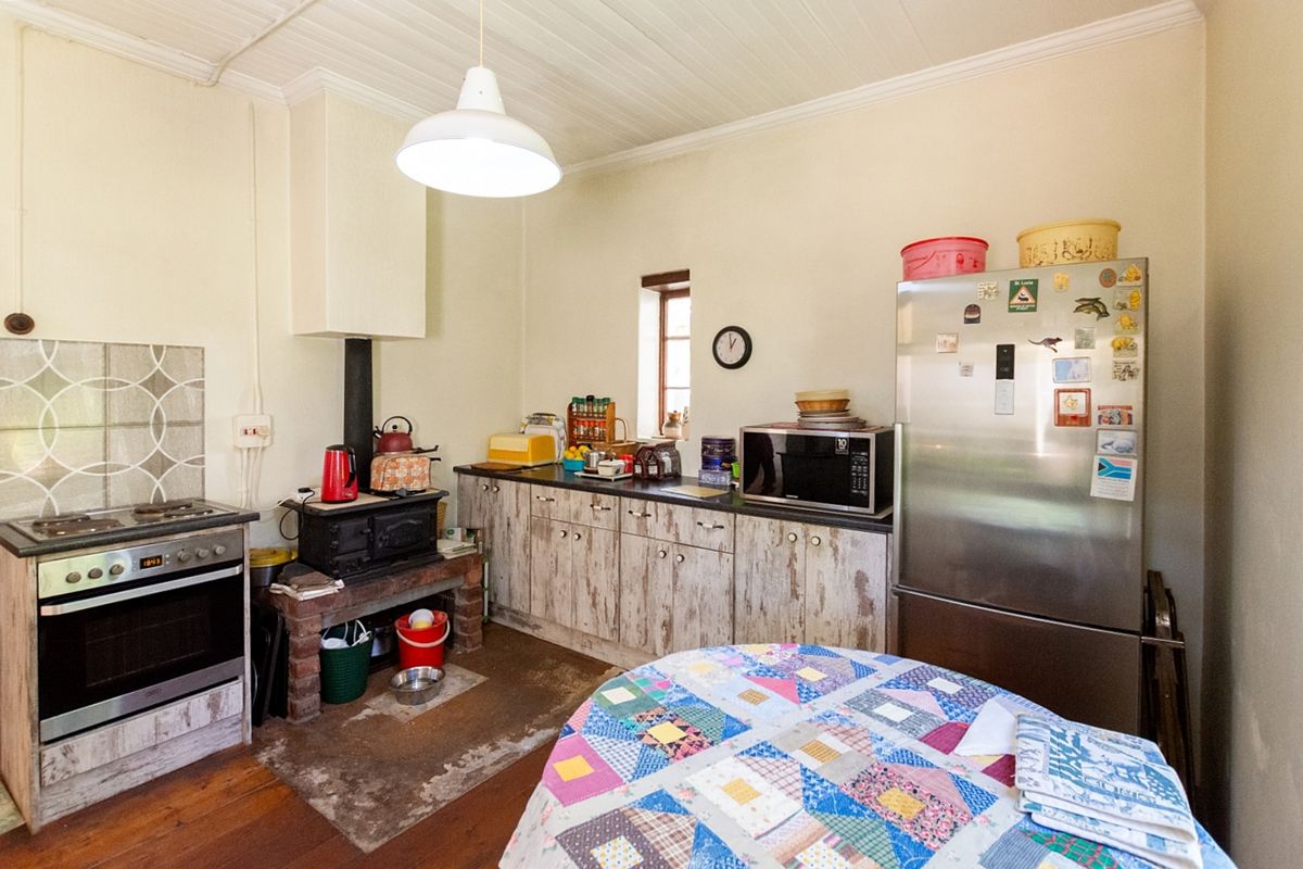 A rustic kitchen featuring a built-in stove, wood-burning fireplace, and weathered cabinetry, offering a traditional and functional cooking space.