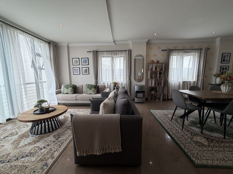 Spacious open-plan living and dining area featuring tiled floors, recessed lighting, and large windows providing ample natural light.