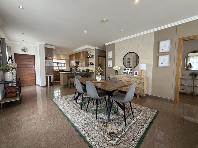 Spacious open-plan living and dining area featuring modern tiled floors, recessed lighting, and a well-appointed kitchen with integrated cabinetry and island.