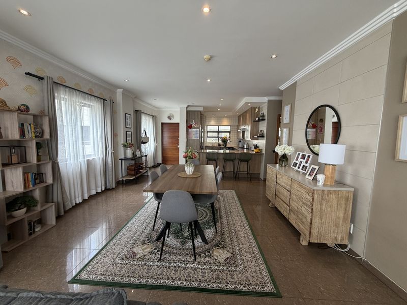 Spacious open-plan living and dining area featuring tiled floors, recessed lighting, and a modern kitchen with a breakfast bar and built-in cabinetry.
