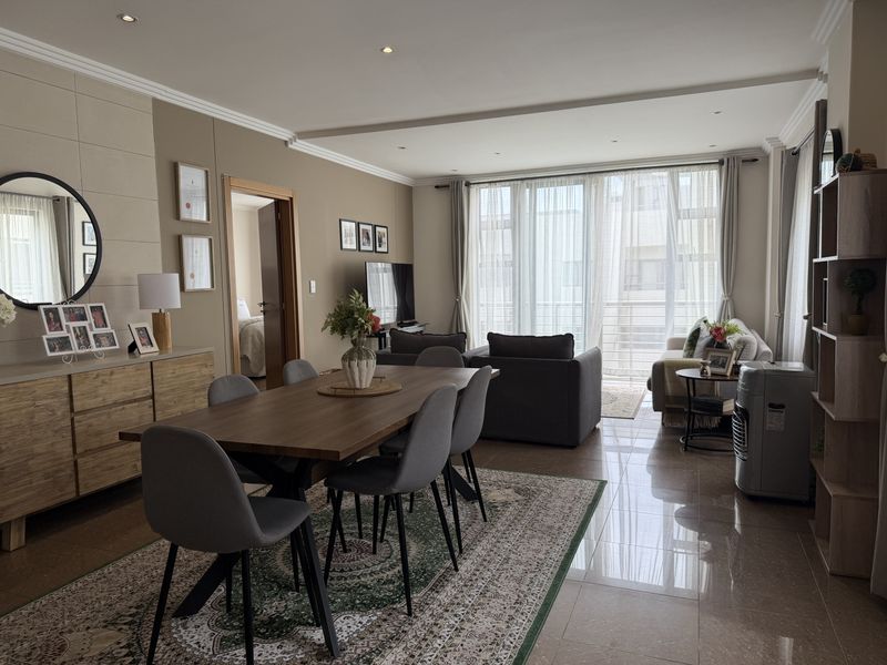 Spacious open-plan living and dining area featuring polished tile flooring, recessed lighting, and large sliding doors leading to a balcony.