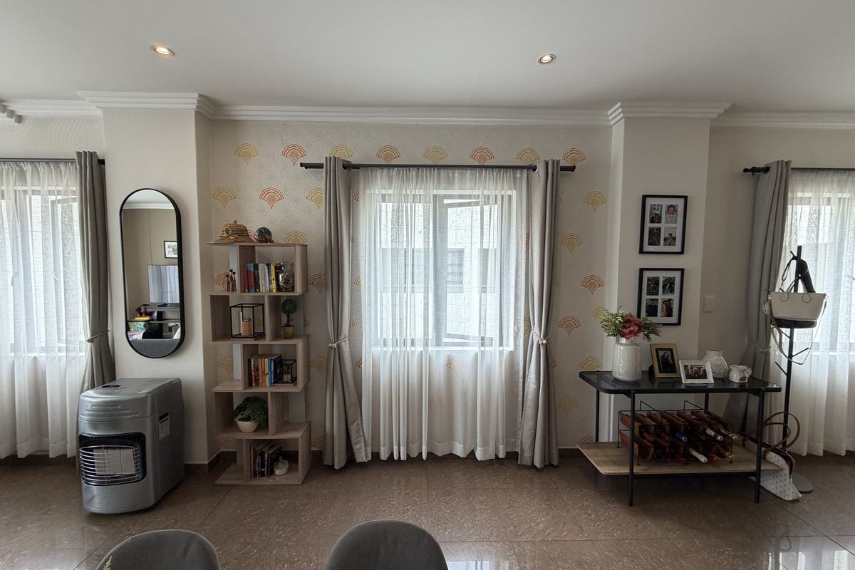 A well-lit living area featuring tiled flooring, recessed downlights, and decorative wallpaper, providing a neutral and inviting space.