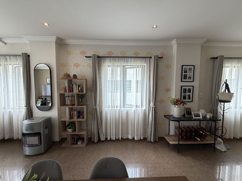 A well-lit living area featuring tiled flooring, recessed downlights, and decorative wallpaper, providing a neutral and inviting space.