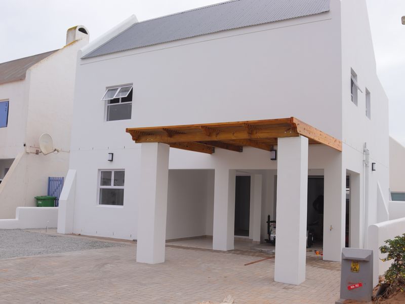 Front elevation of a modern two-story house featuring a timber pergola, paved driveway, and clean white rendered facade.