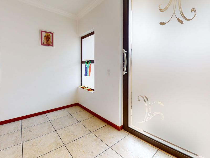 A bright, tiled entrance area featuring a frosted glass sliding door and clean white walls, providing a welcoming transition into the home.