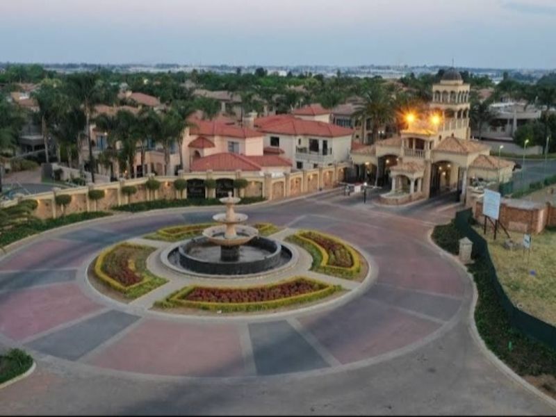 Aerial view of a secure estate entrance featuring a central fountain, paved roundabout, and landscaped surroundings.