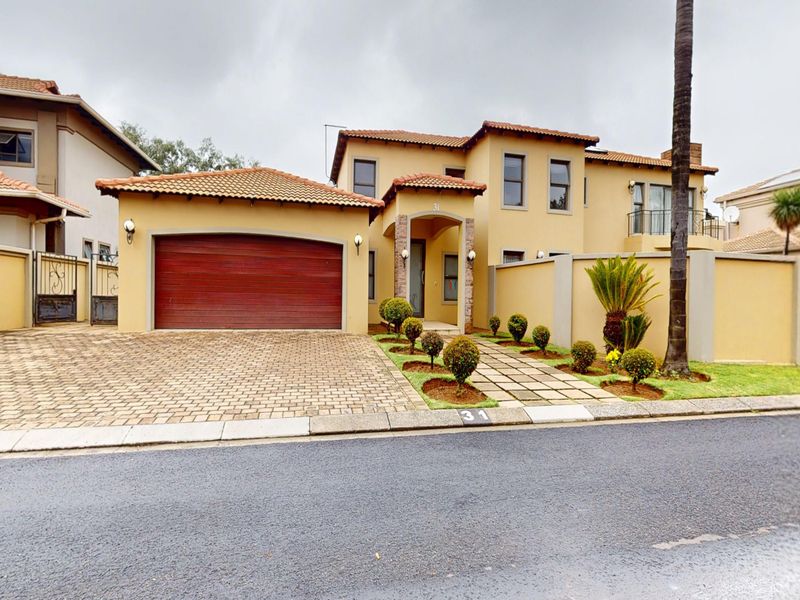 Front elevation of a two-story residential house featuring a double garage, paved driveway, stone-clad entrance, and a balcony.