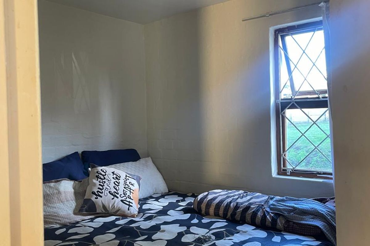 A compact bedroom featuring a leaded glass window and neutral wall finishes, offering a functional space with natural light.