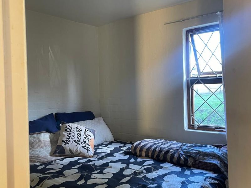 A compact bedroom featuring a leaded glass window and neutral wall finishes, offering a functional space with natural light.