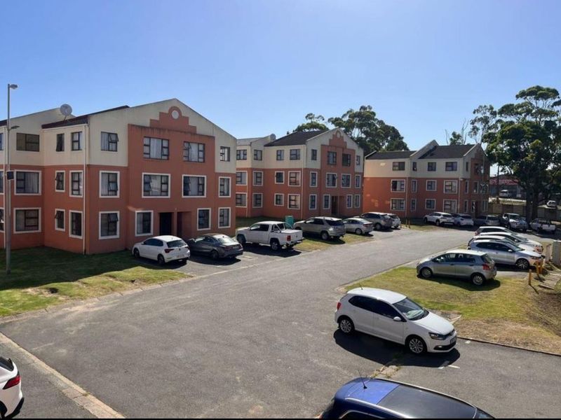 Elevated view of a residential apartment complex featuring multiple multi-story blocks, paved parking areas, and surrounding landscaped grounds.
