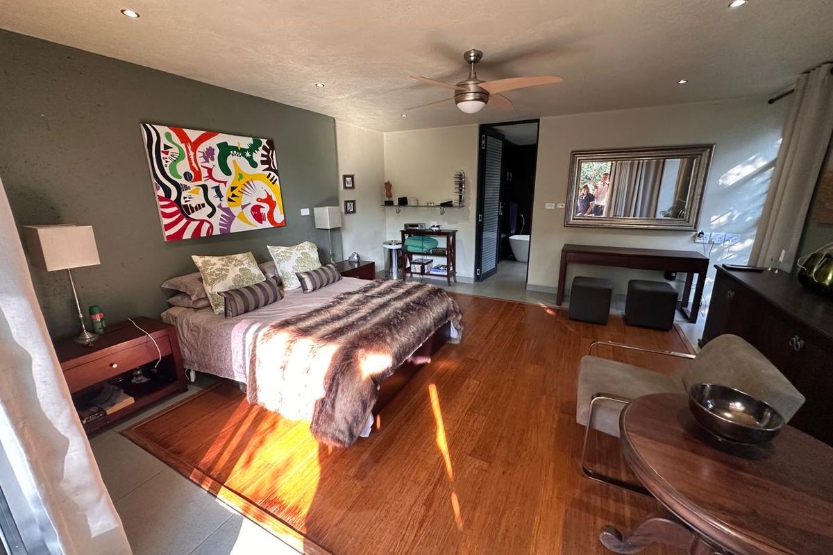 Spacious bedroom featuring warm hardwood flooring, recessed lighting, a ceiling fan, and direct access to an en-suite bathroom.