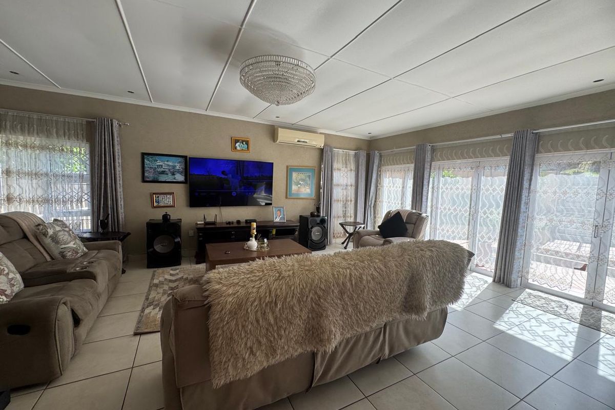 Spacious living room featuring tiled flooring, recessed lighting, a split-system air conditioner, and large sliding glass doors providing access to the outdoor area.
